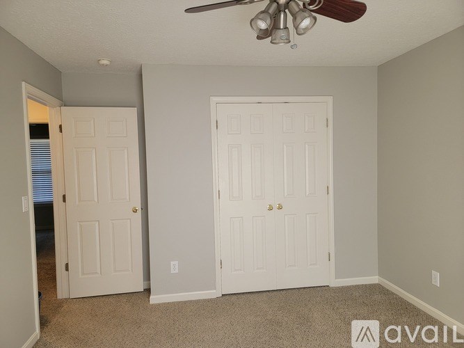 A room with two white doors and a ceiling fan.