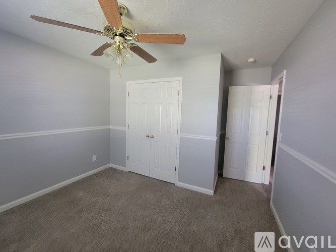 A room with a ceiling fan and two doors.