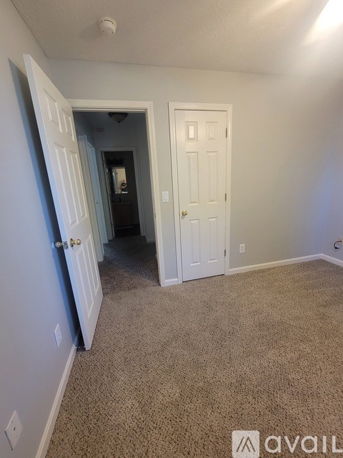 A room with a carpeted floor and a doorway leading to another room.