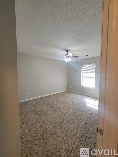A room with a carpet floor and a ceiling fan.