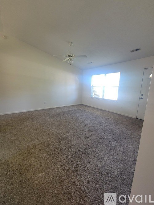 A room with a carpeted floor and a ceiling fan.