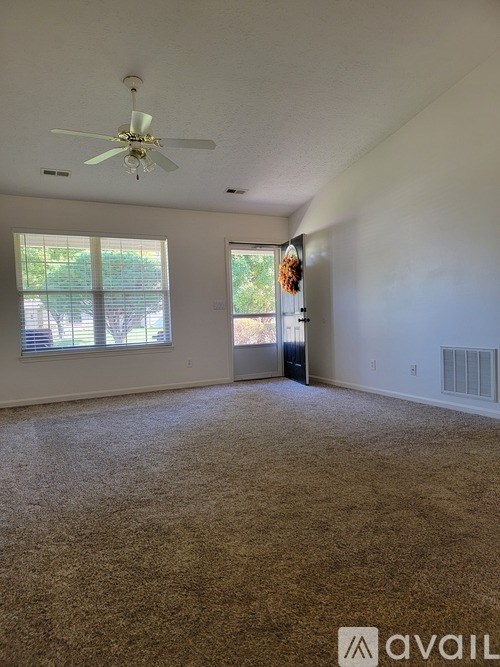 A room with a carpeted floor and a ceiling fan.