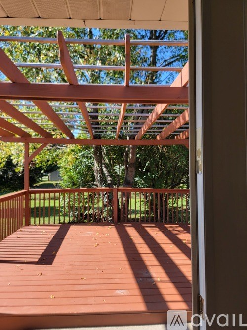 A wooden deck with a pergola and a lawn in the background.