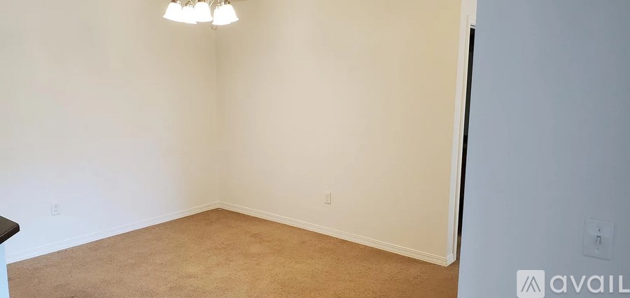 A room with a carpet floor and a chandelier hanging from the ceiling.