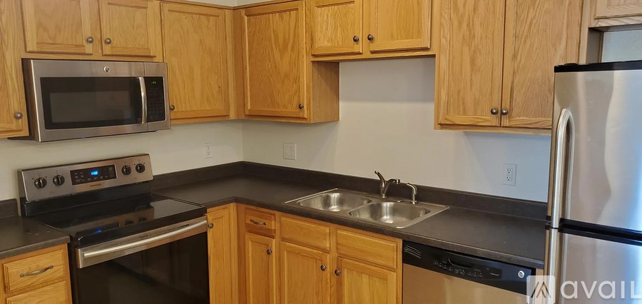 A kitchen with wooden cabinets and a stainless steel refrigerator.