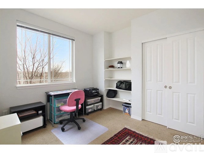 A room with a desk, chair, and shelves.