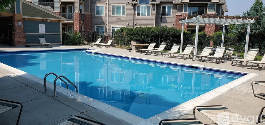 A pool surrounded by chairs and a building in the background.