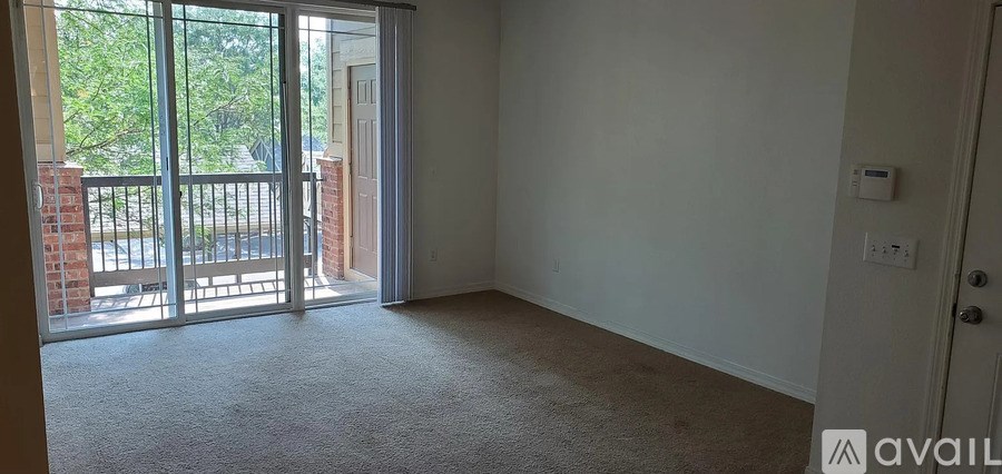 A room with a carpeted floor and a door leading to a balcony.