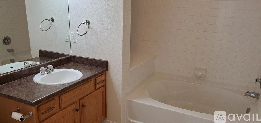 A bathroom with a sink, mirror, and bathtub.