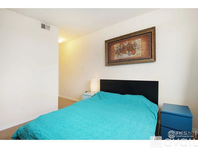 A bedroom with a blue bedspread and a framed picture on the wall.