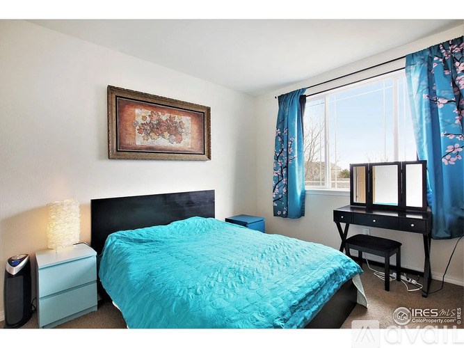 A bedroom with a blue bedspread and a painting on the wall.