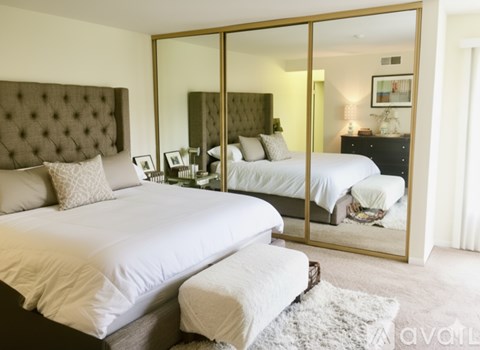A bedroom with a large bed and a mirrored wardrobe.