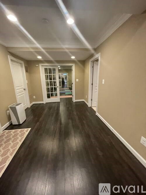 A hallway with dark wood floors and white walls.