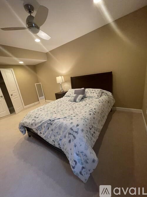 A bedroom with a bed, a ceiling fan, and a lamp.