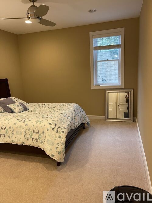 A bedroom with a bed, a window, and a ceiling fan.
