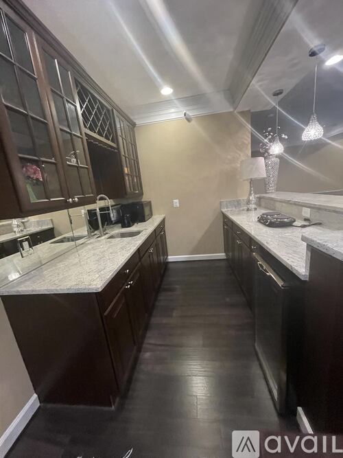 A kitchen with dark wood cabinets and a marble countertop.