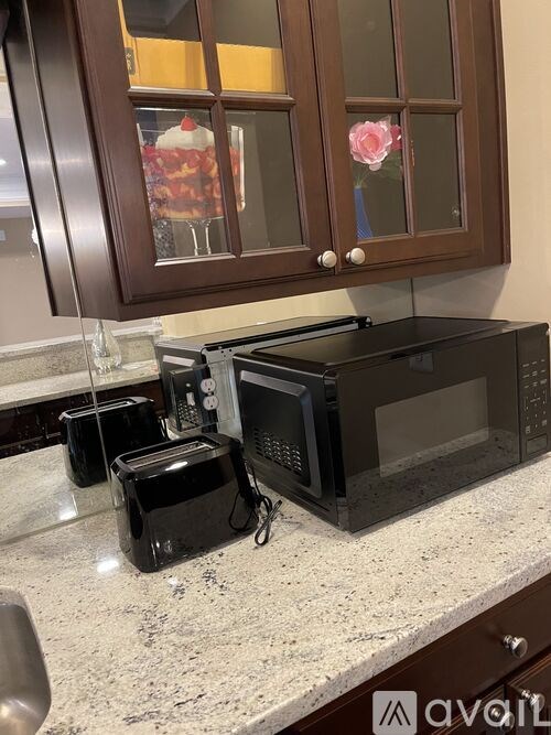 A black microwave oven is on a granite countertop.
