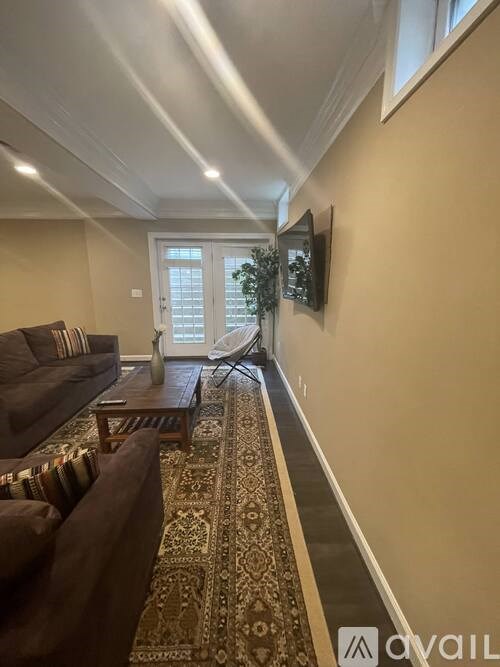 A living room with a brown couch and a rug.