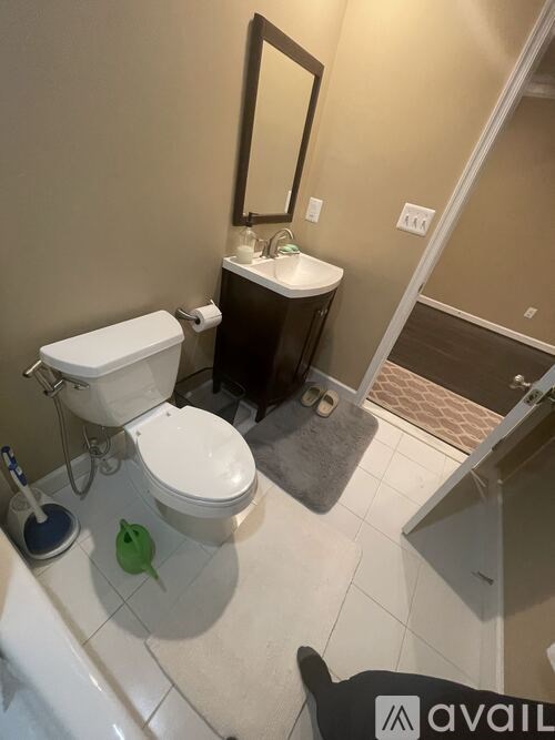 A bathroom with a toilet, sink, and mirror.