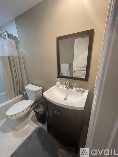 A bathroom with a toilet, sink, and mirror.