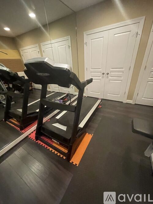 A gym with a row of treadmills and a row of lockers.