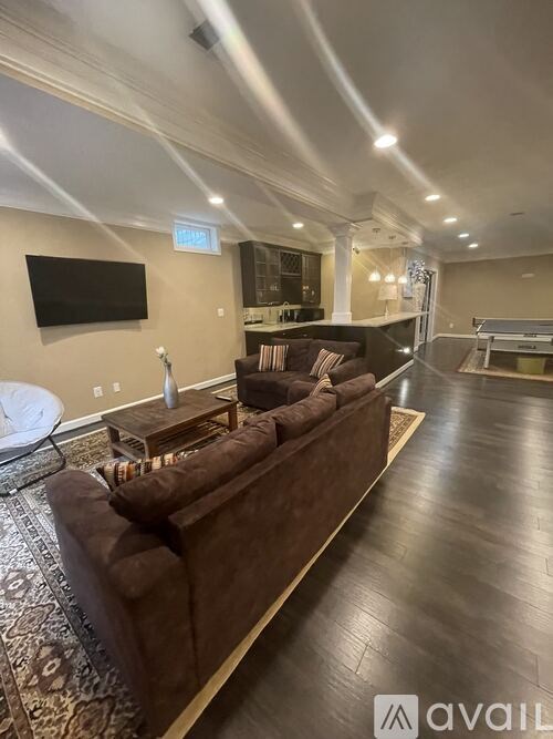 A living room with a dark brown couch and a flat screen TV mounted on the wall.
