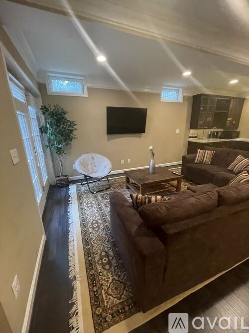 A living room with a brown couch and a flat screen TV mounted on the wall.