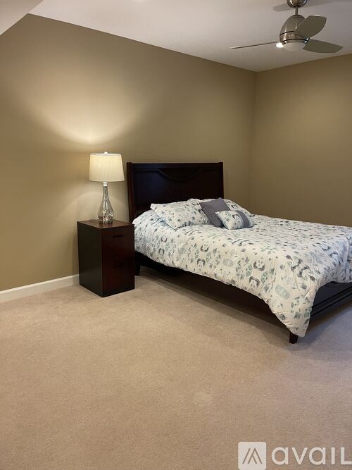 A bedroom with a bed, nightstand, and lamp.