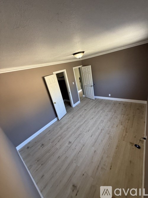A room with wooden flooring and two white doors.