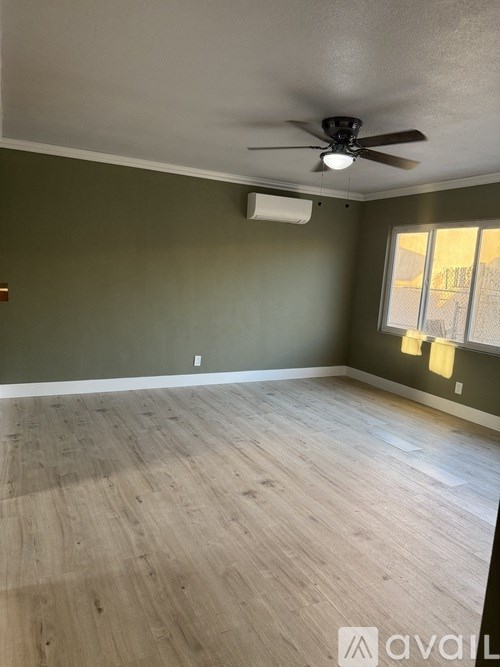 A room with a ceiling fan and wooden flooring.