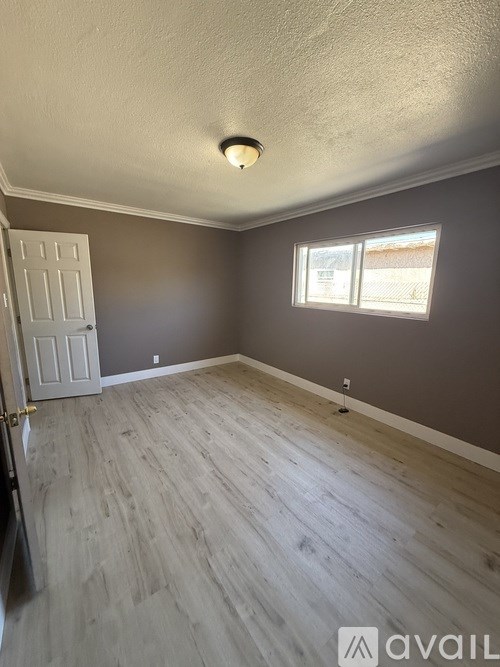 A room with a white door and a window with a view of a building outside.