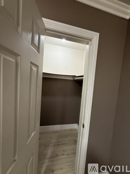 A white door is open to a room with brown walls.