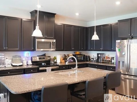 A kitchen with dark brown cabinets and a granite countertop.