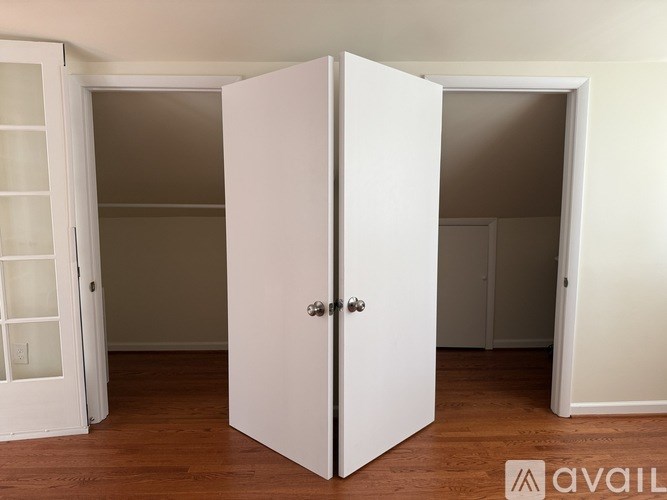 A white wardrobe with a glass door is in a room with wooden flooring.