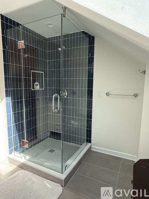 A shower with a glass door and a white mat on the floor.