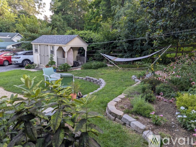 A backyard with a hammock and a small building.