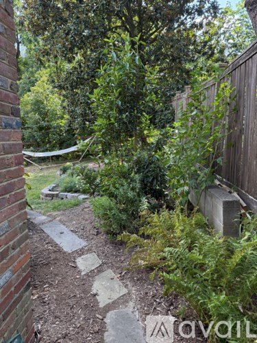 A garden path with a brick wall on the left and a wooden fence on the right.