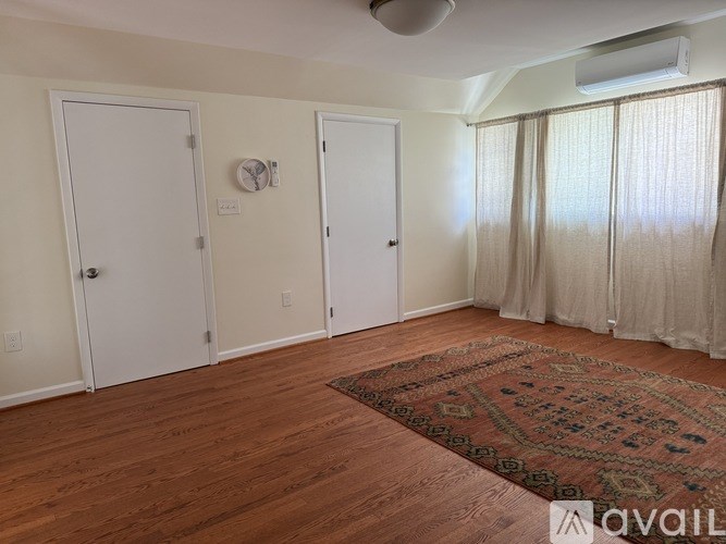A room with a rug on the floor and a clock on the wall.