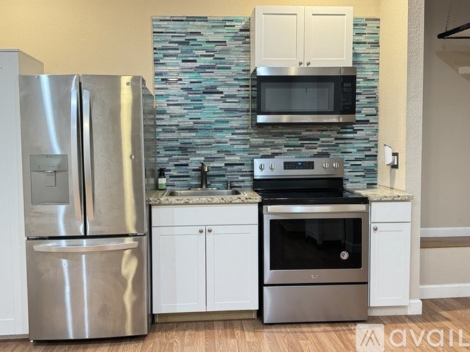 A kitchen with a stainless steel refrigerator, microwave, and oven.
