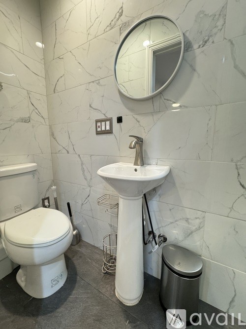 A bathroom with a toilet, sink, and mirror.