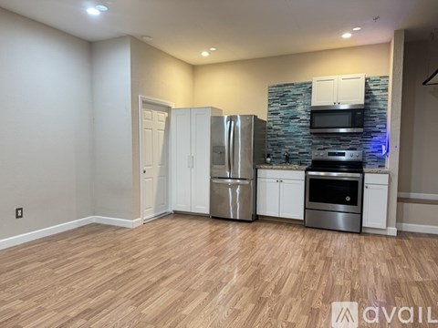 A kitchen with white cabinets and a wooden floor.