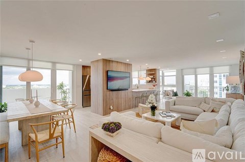 A modern living room with a large white sofa and a wooden dining table.