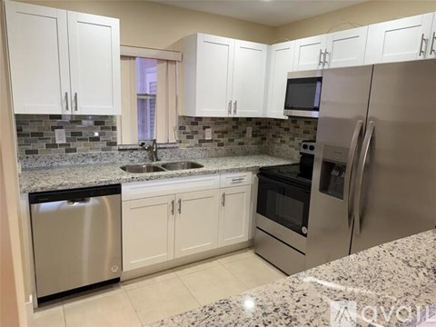 A kitchen with white cabinets and granite countertops.