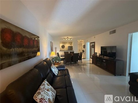 A living room with a black leather couch and a painting on the wall.