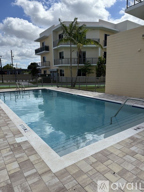 A swimming pool in front of a building with a balcony.