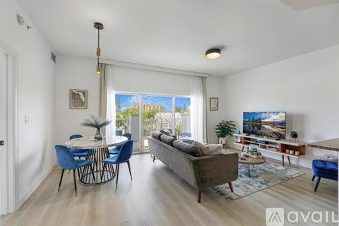 A living room with a blue sofa and a dining table with chairs.
