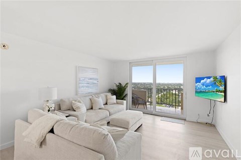 A living room with a large couch and a flat screen TV mounted on the wall.