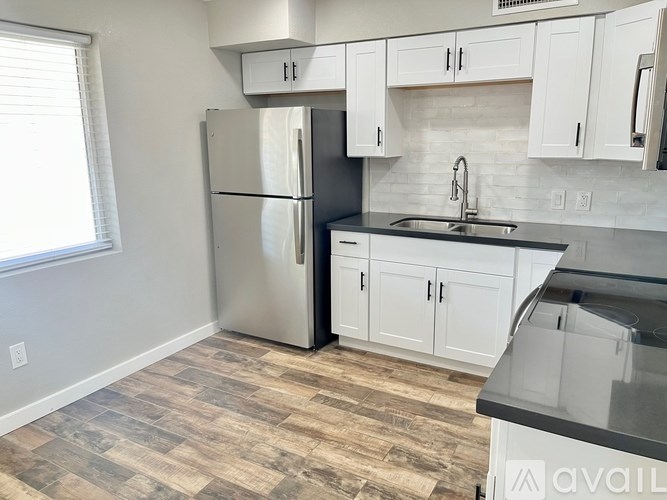 A kitchen with a refrigerator, cabinets, and a sink.