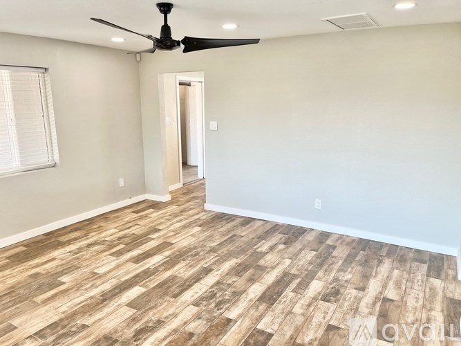 A room with a ceiling fan and wooden flooring.