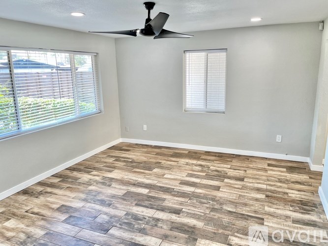 A room with a ceiling fan and wood flooring.